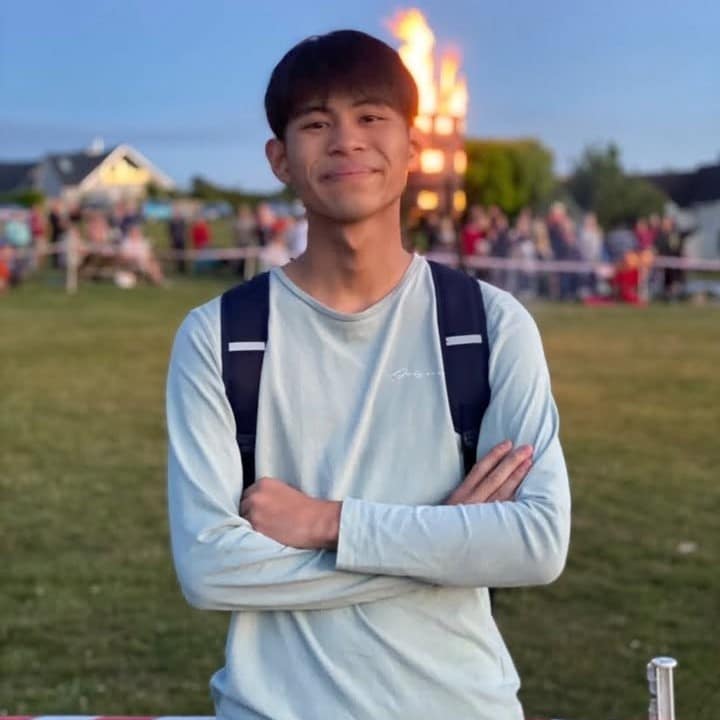 Young person at outdoor event, smiling with arms crossed, representing Eating Matters community support